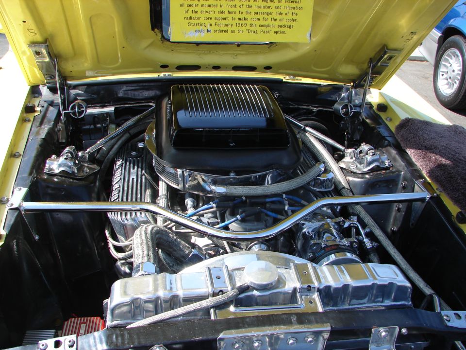 Yellow car engine bay with chrome details and a black air cleaner
