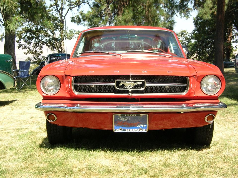 Red 1965 Ford Mustang front view with chrome grille and Mustang emblem