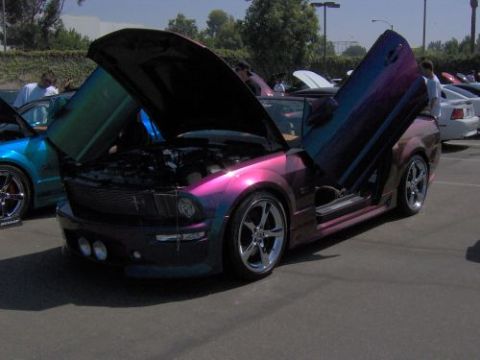 1991 Ford Taurus - A customized Ford Mustang with an iridescent paint job is displayed with its hood and doors open.