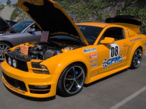 1991 Ford Taurus - A bright yellow custom Ford Mustang is displayed with its hood open, racing decals and modifications.