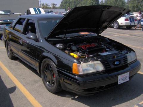 1991 Ford Taurus - A black 1991 Ford Taurus is parked with its hood open, revealing the engine bay and its front end.