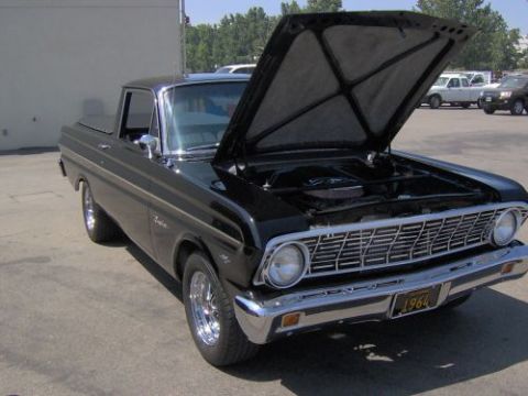 1991 Ford Taurus - Black 1964 Ford Falcon Ranchero pickup with hood open, parked outdoors with other vehicles in background.