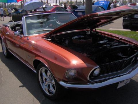1991 Ford Taurus - This orange convertible, likely a 1969 model, is displayed with its hood open, revealing the engine compartment.