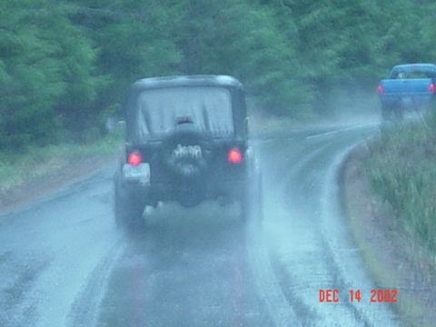 1989 Ford Bronco - Two vehicles drive on a wet road during a rainstorm, with a date stamp of DEC 14 2002.