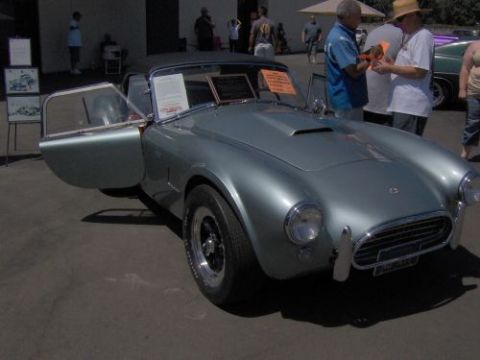 1991 Ford Taurus - A silver Shelby Cobra is displayed with its door open, attracting attention from onlookers.
