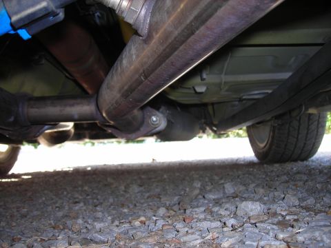2003 Ford Mustang - The underside of a vehicle, showing the exhaust pipe and a rear wheel, is captured from a low angle.