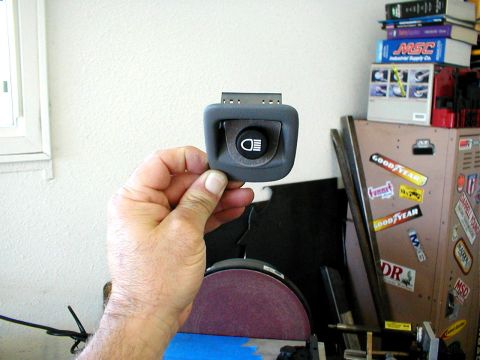 1996 Ford Bronco - A hand holds a gray headlight switch with a fog light icon, likely a replacement part.