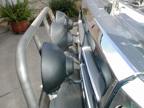 1996 Ford Bronco - A close-up view of auxiliary off-road lights mounted on a custom roll bar, attached to the front of a vehicle.