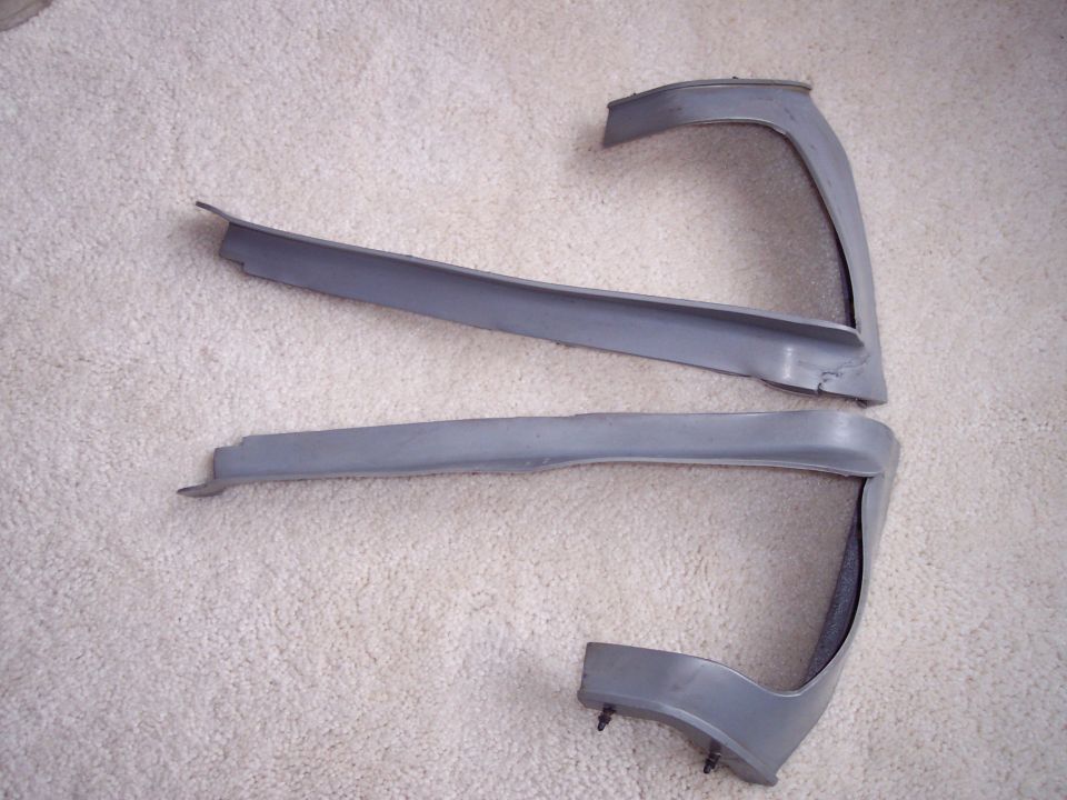 Pair of grey A-pillar interior trim panels with retaining clips laid on cream carpet