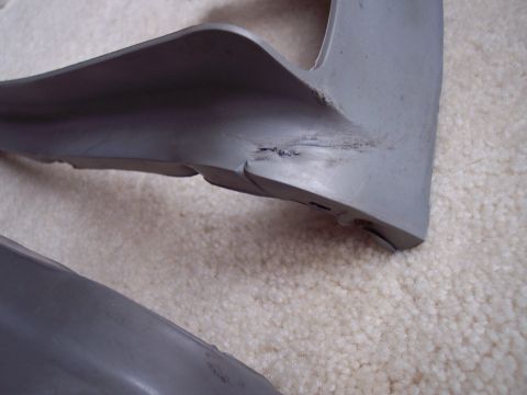 1968 Chrysler Town & Country - A close-up view of a damaged gray plastic trim piece, possibly a bumper spacer, showing cracks and imperfections.