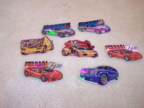 1968 Chrysler Town & Country - Various car stickers are displayed on a carpeted surface, including several exotic sports cars and an SUV.