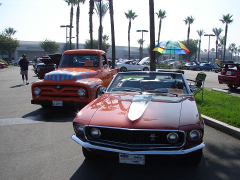 1992 Ford Taurus - A red 1969 convertible and an orange pickup truck are parked at an outdoor event with palm trees.