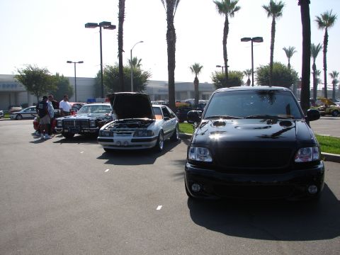 1992 Ford Taurus - A black pickup truck is parked in a lot with other vehicles and palm trees.