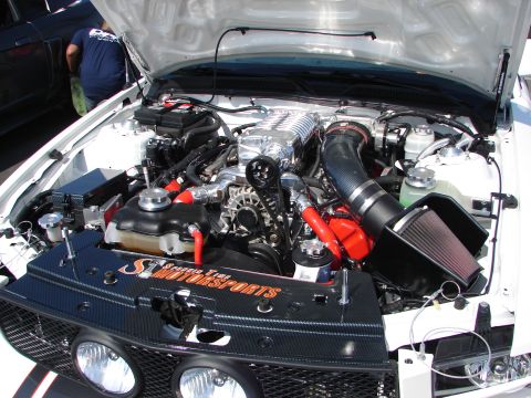 1992 Ford Taurus - The engine bay of a modified vehicle, a prominent supercharger and custom air intake system.