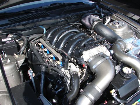 1992 Ford Taurus - Close-up view of a modified engine bay, a carbon fiber intake manifold and a high-flow air filter.