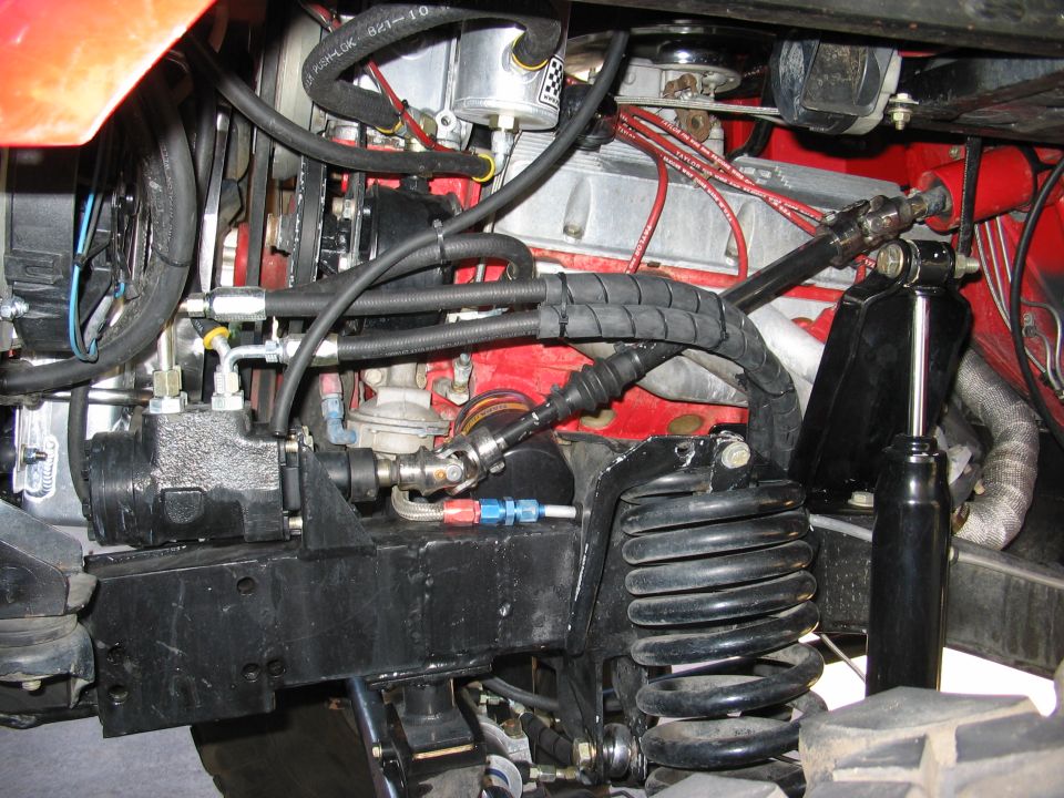 Engine bay detail showing power steering hoses, coil spring and shock absorber