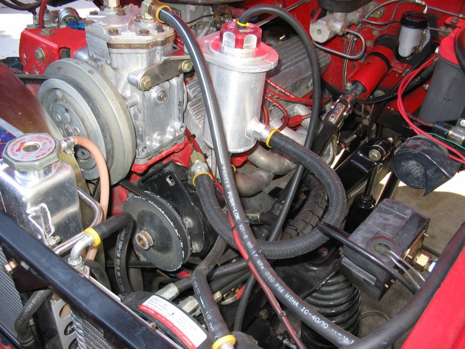 Engine compartment with air conditioning compressor and fluid reservoir