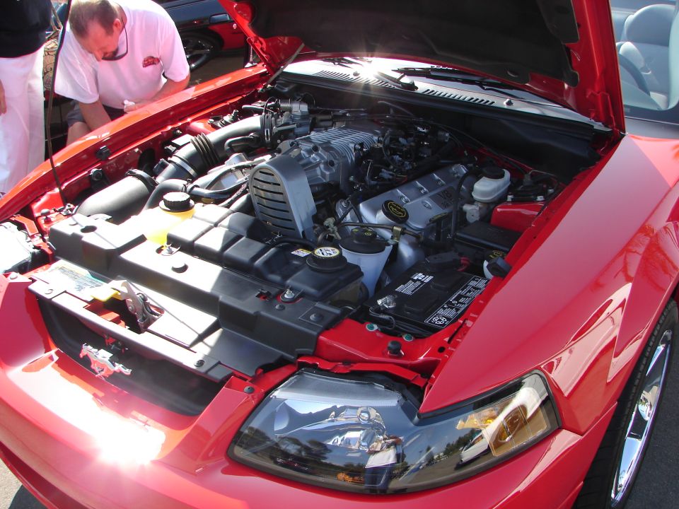 Red Ford Mustang engine bay with a supercharger visible