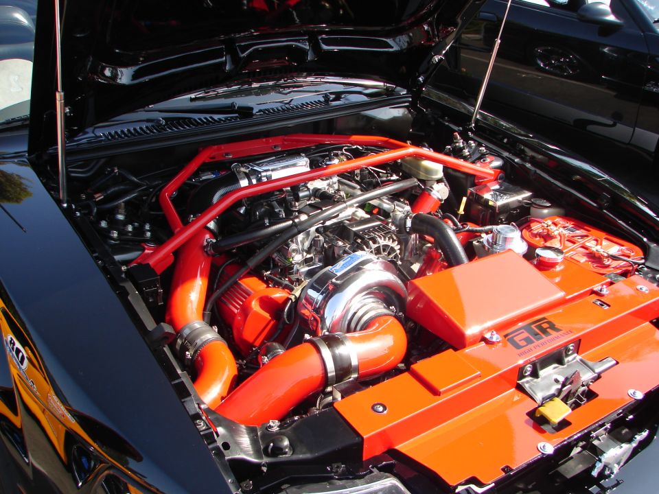 Engine bay with turbocharger, red intake piping, and orange accents