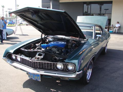 1992 Ford Taurus - A green 1970 Ford Torino GT is parked with its hood open, revealing the engine bay and a blue air cleaner.