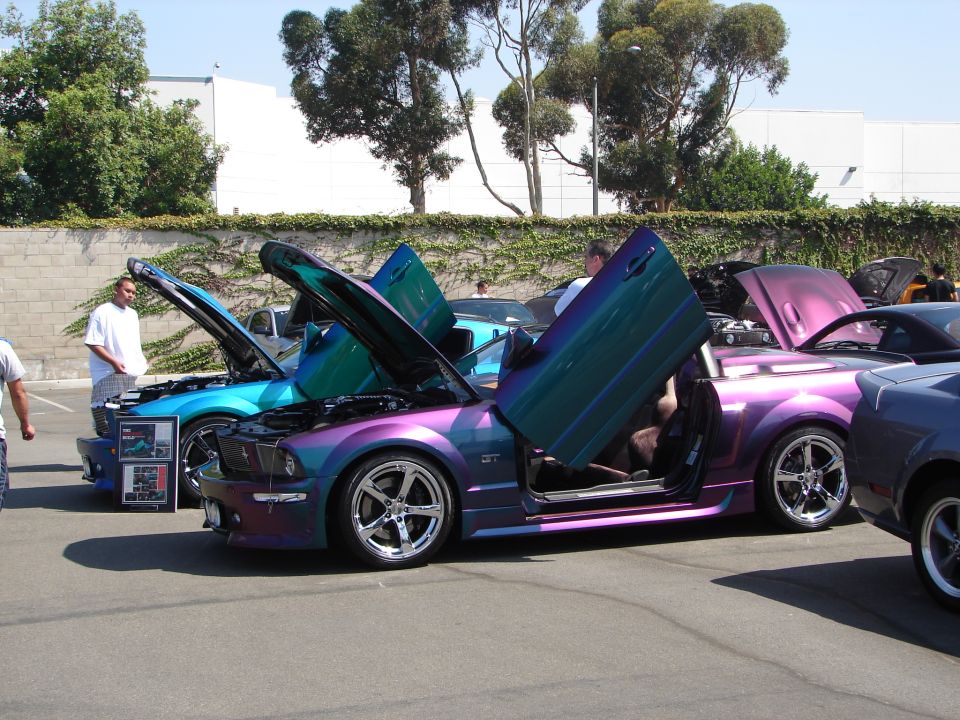 Purple and teal Ford Mustang with butterfly doors open, showing custom paint and wheels