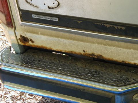 1986 Ford Bronco - Close-up of a 1986 Ford Bronco's rear tailgate showing rust and an 'ELECTRONIC FUEL INJECTION' badge.