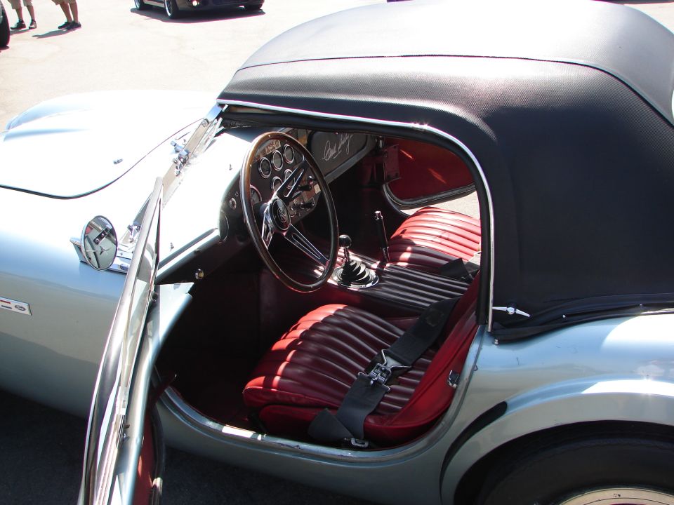 Interior view of a classic convertible with red seats and a wood-rimmed steering wheel