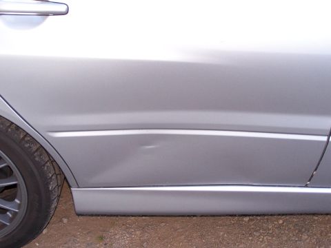 1995 Ford Probe - A dent is visible on the lower section of a silver car door, with the rear tire and door handle also in view.