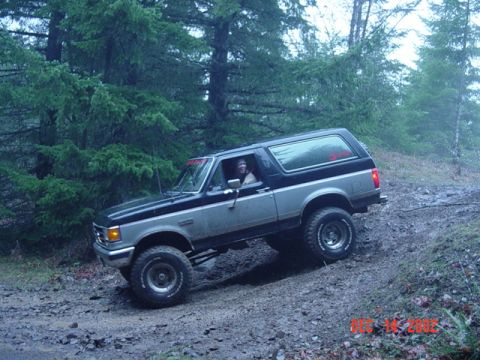 1989 Ford Bronco - A two-tone Ford Bronco navigates a muddy, wooded trail in this off-road photo.