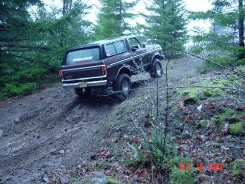 1989 Ford Bronco - Ford Bronco navigates a steep, muddy trail surrounded by trees. Date stamp reads 12/14/02.