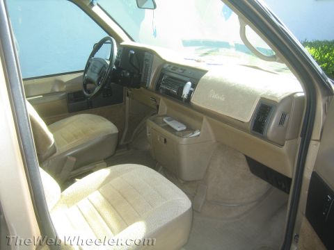 1968 Ford Mustang - The interior of this van features tan upholstery and a tan dashboard with a car stereo and remote control.
