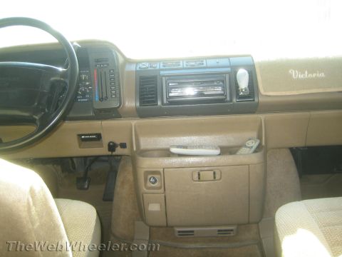 1968 Ford Mustang - The interior dashboard of a van, the radio, climate controls, and the name "Victoria" embroidered on the dash.