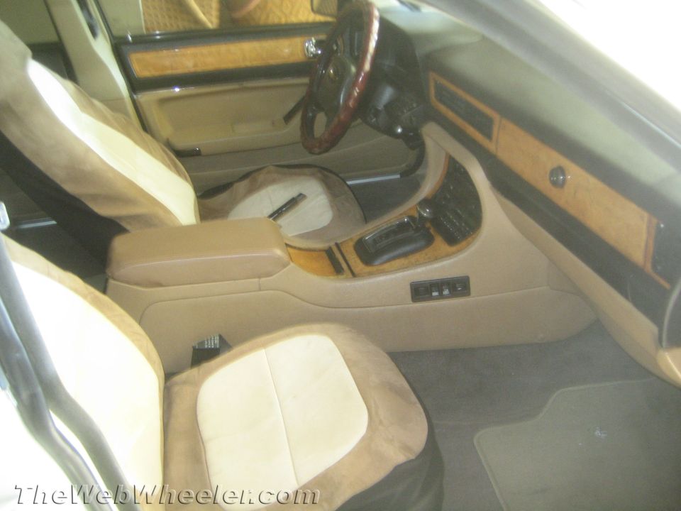 Car interior showing tan and brown seats, wood trim dashboard, and steering wheel