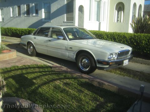 1968 Ford Mustang - A white sedan is parked on a driveway in front of a house.