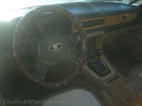 1968 Ford Mustang - The dashboard and center console of a Jaguar show wood grain accents and a leather-wrapped steering wheel.