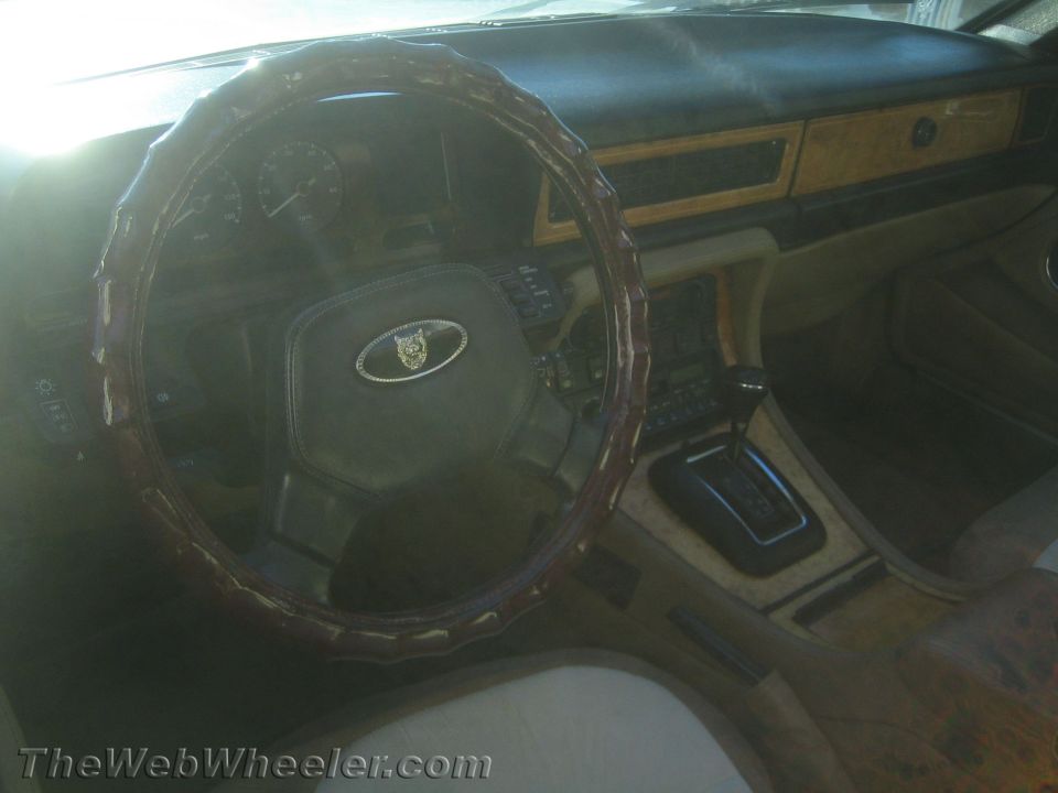 Interior shot of a Jaguar with wood trim, leather steering wheel cover, and automatic shifter