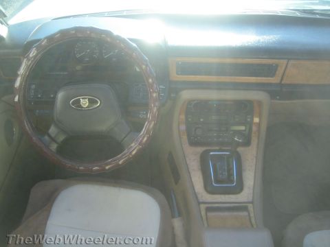 1968 Ford Mustang - The interior of a Jaguar shows a wood-trimmed dashboard and a leather-covered steering wheel.