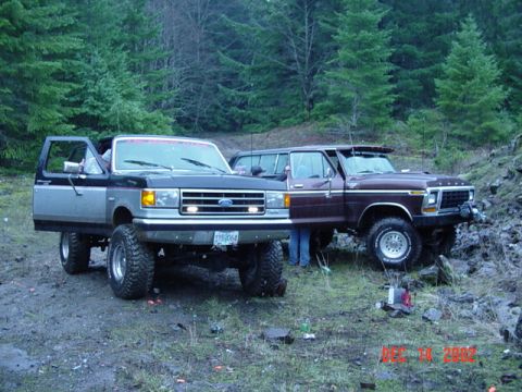 1989 Ford Bronco - Two Ford Broncos are parked on a dirt trail surrounded by trees. The date 12/14/2002 is visible in the lower right corner.