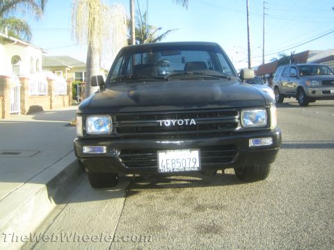 1968 Ford Mustang - Front view of a black Toyota pickup truck parked on a residential street. Another SUV is visible in the background.