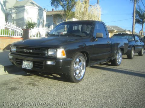 1968 Ford Mustang - Black Toyota pickup truck with custom chrome wheels is parked on a residential street.