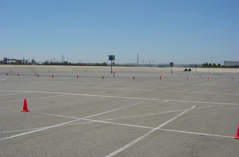 Autocross course with orange cones and white lines on asphalt under a clear blue sky