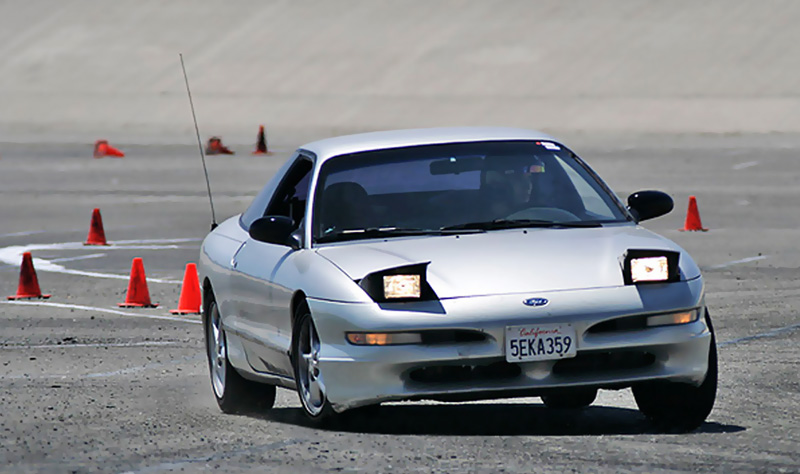 Silver 1993 Ford Probe autocrossing, pop-up headlights up, California plate 5EKA359