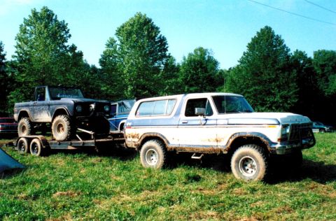 1978 Ford Bronco - Two Ford Broncos are visible, one is on a trailer being towed by the other, both appear muddy.