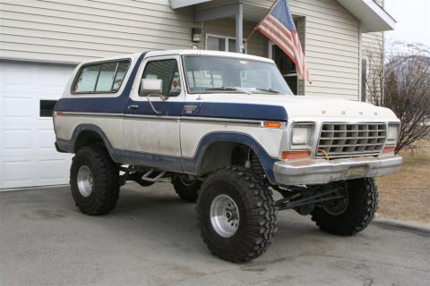 1978 Ford Bronco - Lifted 1978 Ford Bronco with off-road tires sits in front of a house with an American flag.
