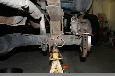 1978 Ford Bronco - Close-up view of a vehicle's rear suspension and braking system, elevated on a jack for maintenance.