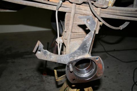 1978 Ford Bronco - Close-up of a rusty vehicle suspension part, likely a spindle or knuckle, supported by a jack.