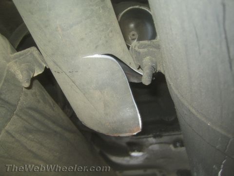 1990 Ford Bronco - Close-up underside of a vehicle showing a metal driveshaft, exhaust pipe and undercarriage components.