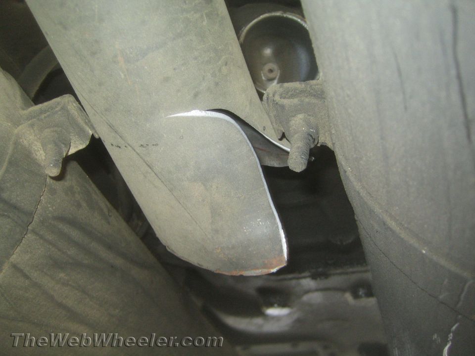 Underside view of a vehicle showing a driveshaft and exhaust pipe