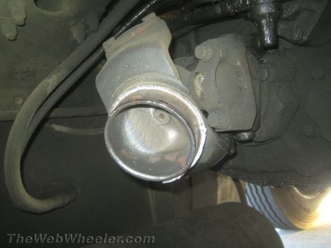 1990 Ford Bronco - Underside close-up of a driveshaft yoke and U-joint mounted to a differential beneath a vehicle.
