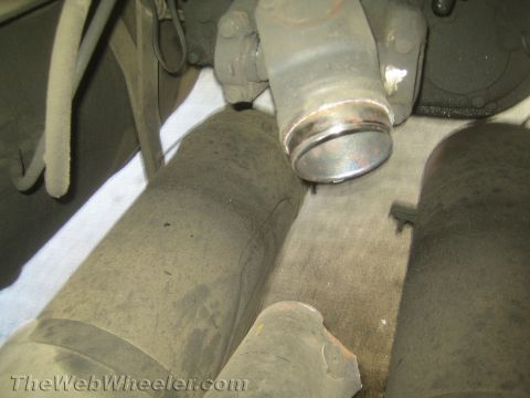 1990 Ford Bronco - Underside view of a metal driveshaft slip yoke positioned between two black bushings beneath a vehicle.